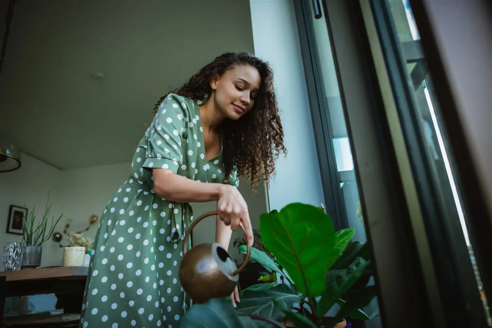 Dominican woman,watering flowers in her apartment