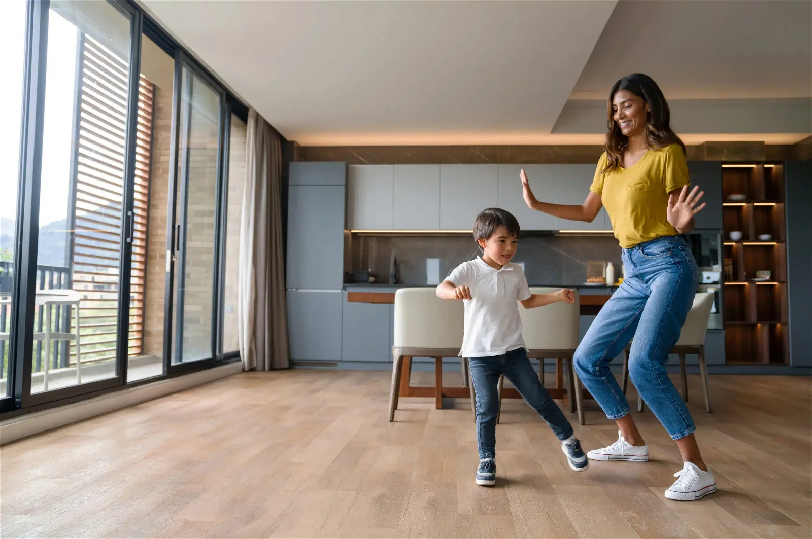 Happy mother having fun dancing with her son at home