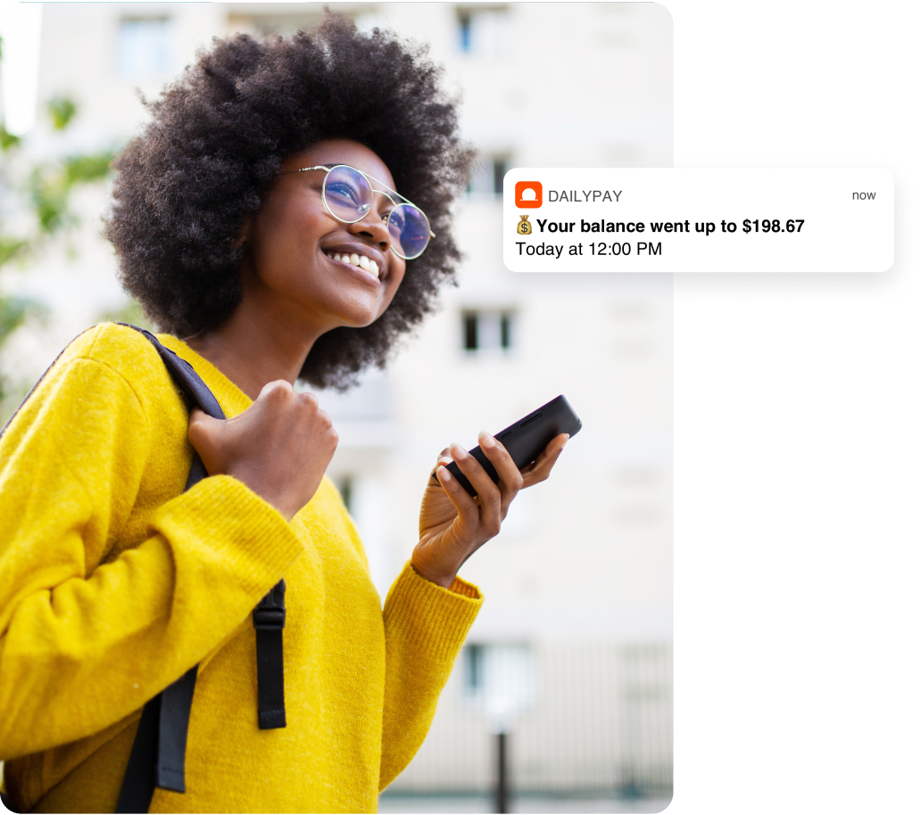 A person holding a smartphone receives a notification from DailyPay stating, "Your balance went up to $198.67 Today at 12:00 PM.